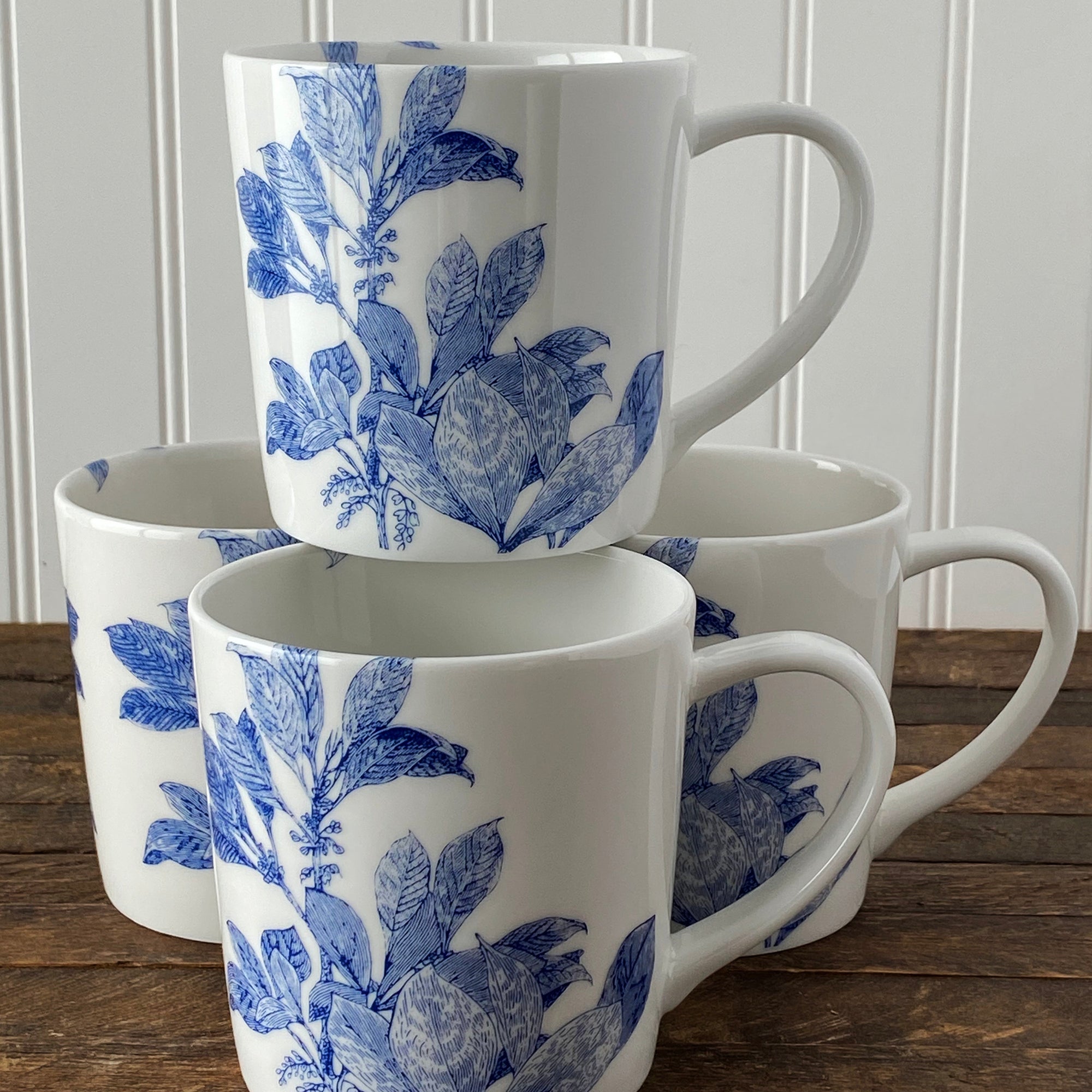 Four blue and white mugs on a wooden table.