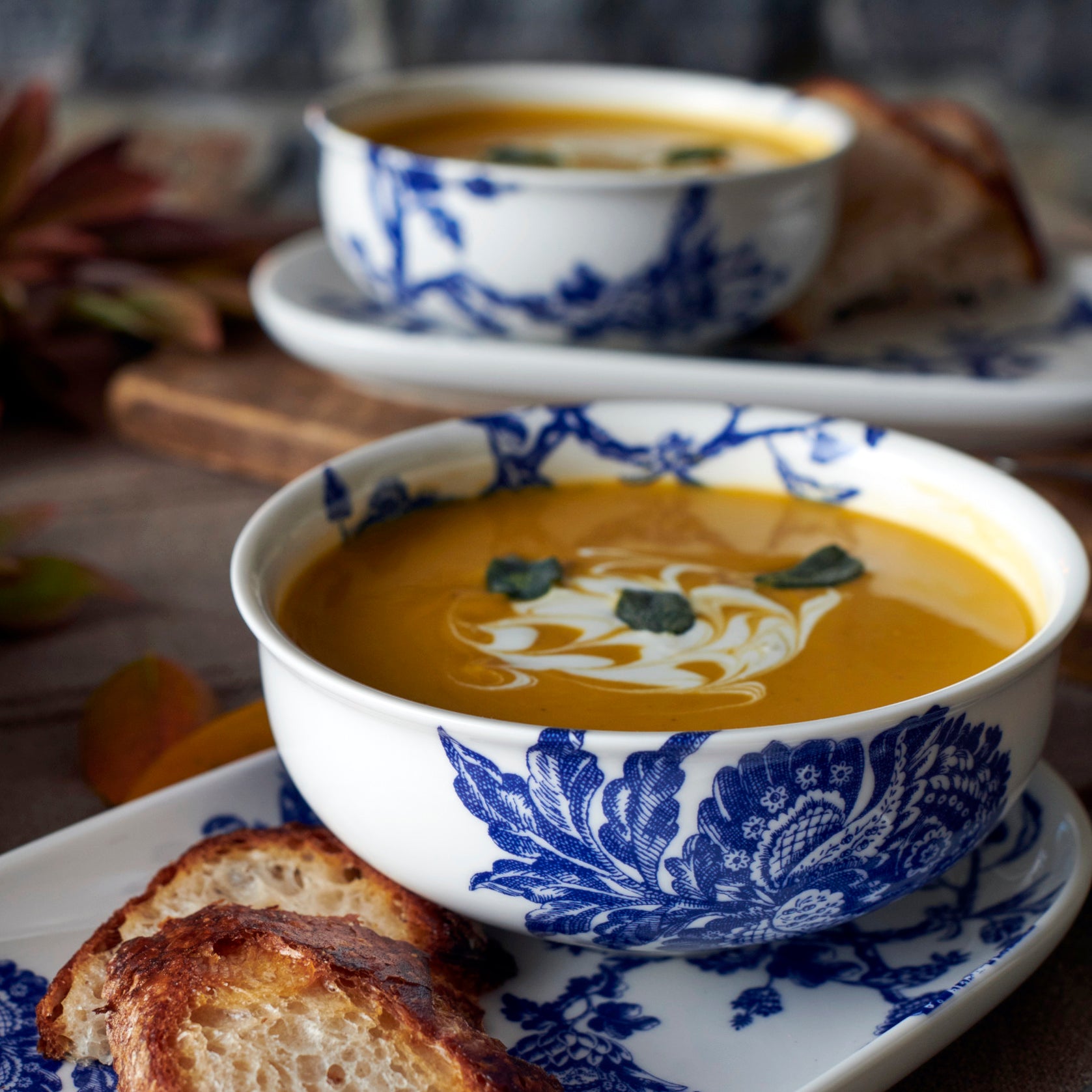 Two bowls of pumpkin soup served with slices of toasted bread.