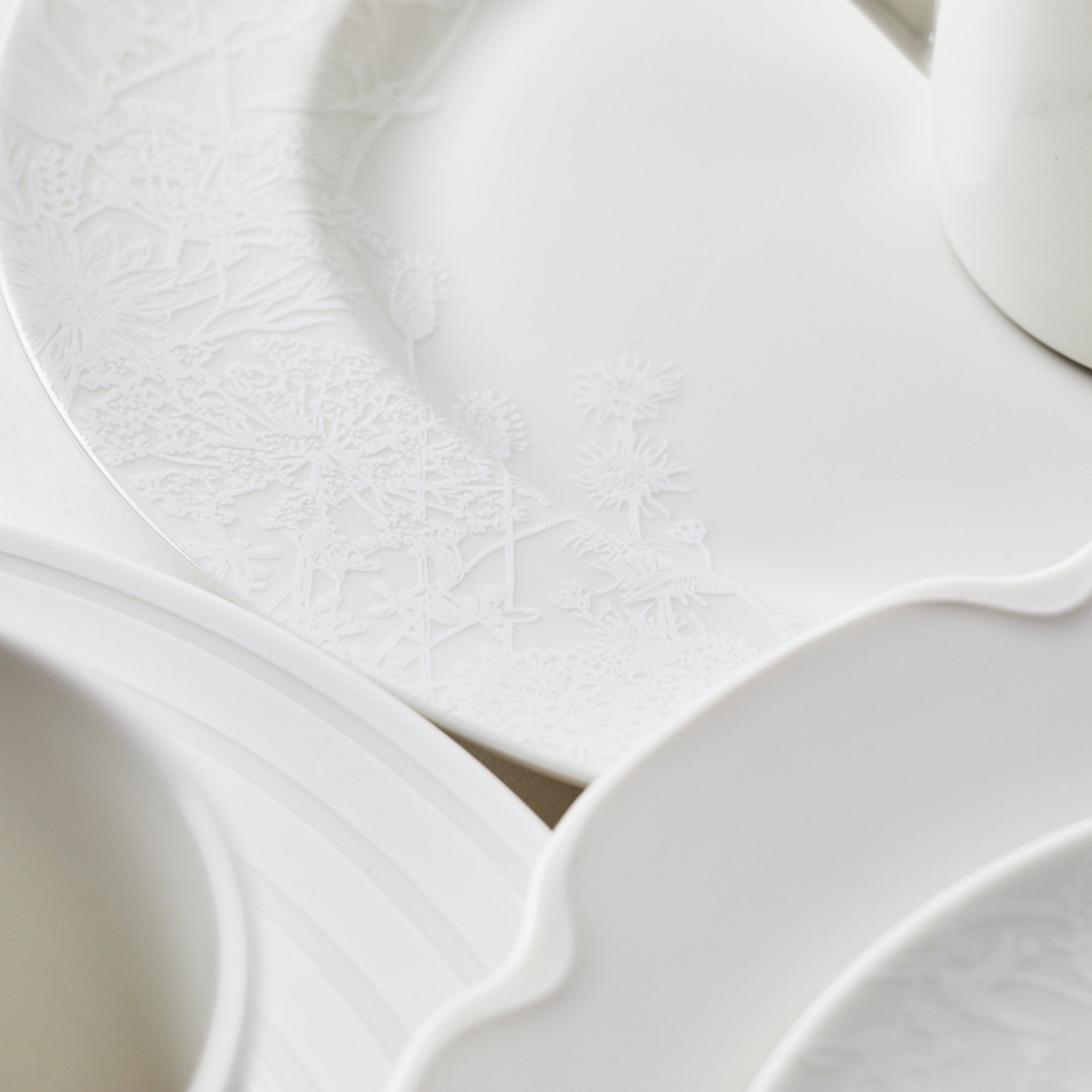 Elegant white porcelain dinnerware with embossed floral design.