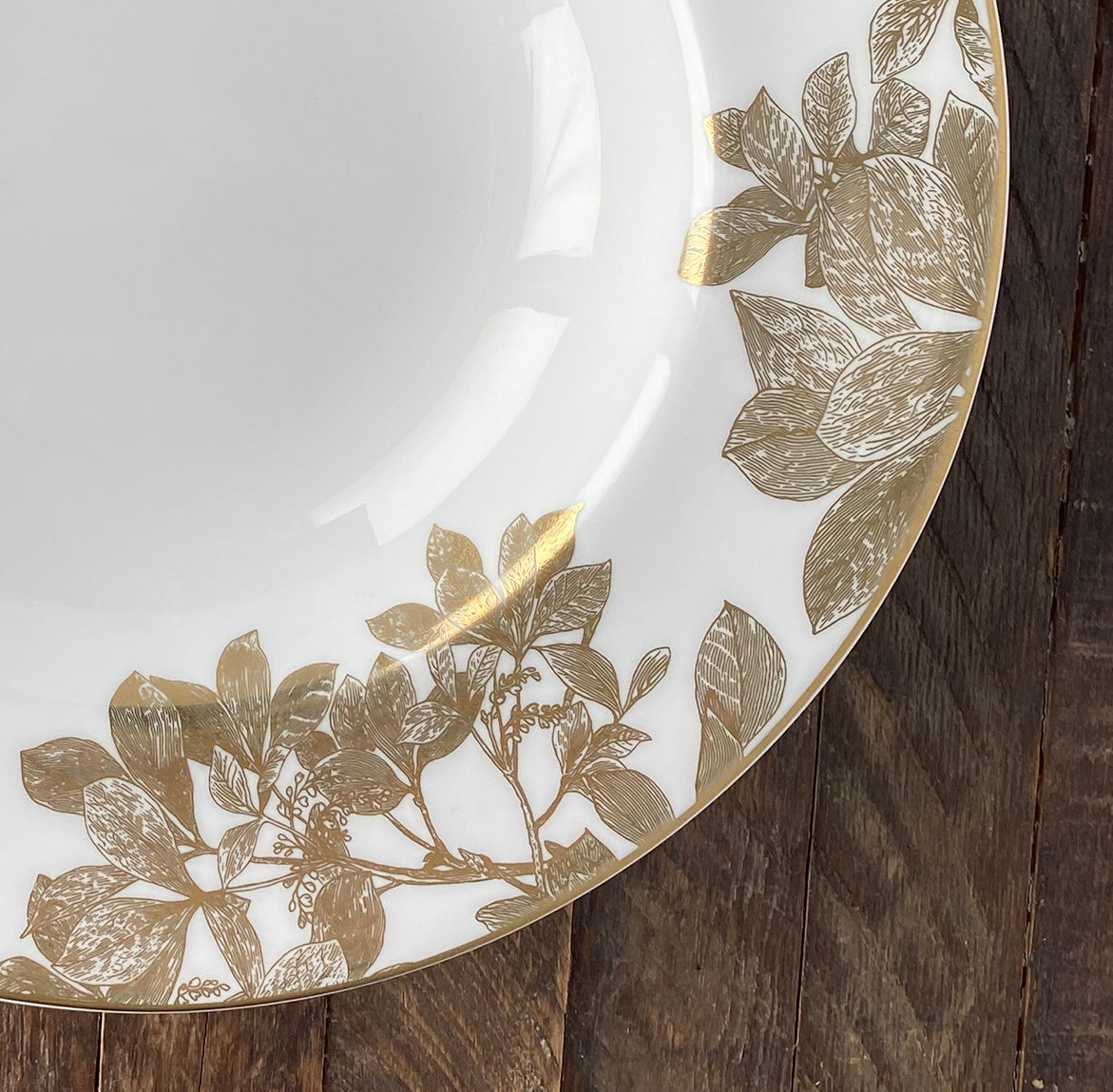 A close up photo of the bone china Arbor Gold Rimmed Soup Bowl by Caskata shows off the intricate branches of the design.