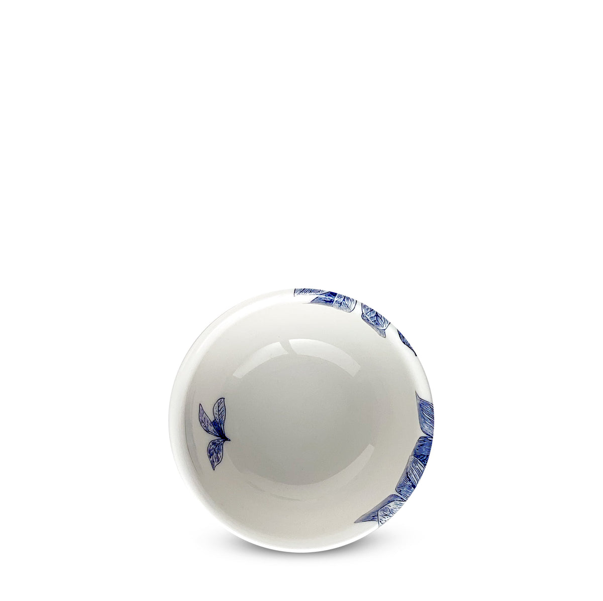 A small white ceramic bowl with blue floral designs on the rim, featuring butterflies and leafy branches. The Arbor Snack Bowl from Caskata Artisanal Home is dishwasher and microwave safe and is centered empty against a white background.