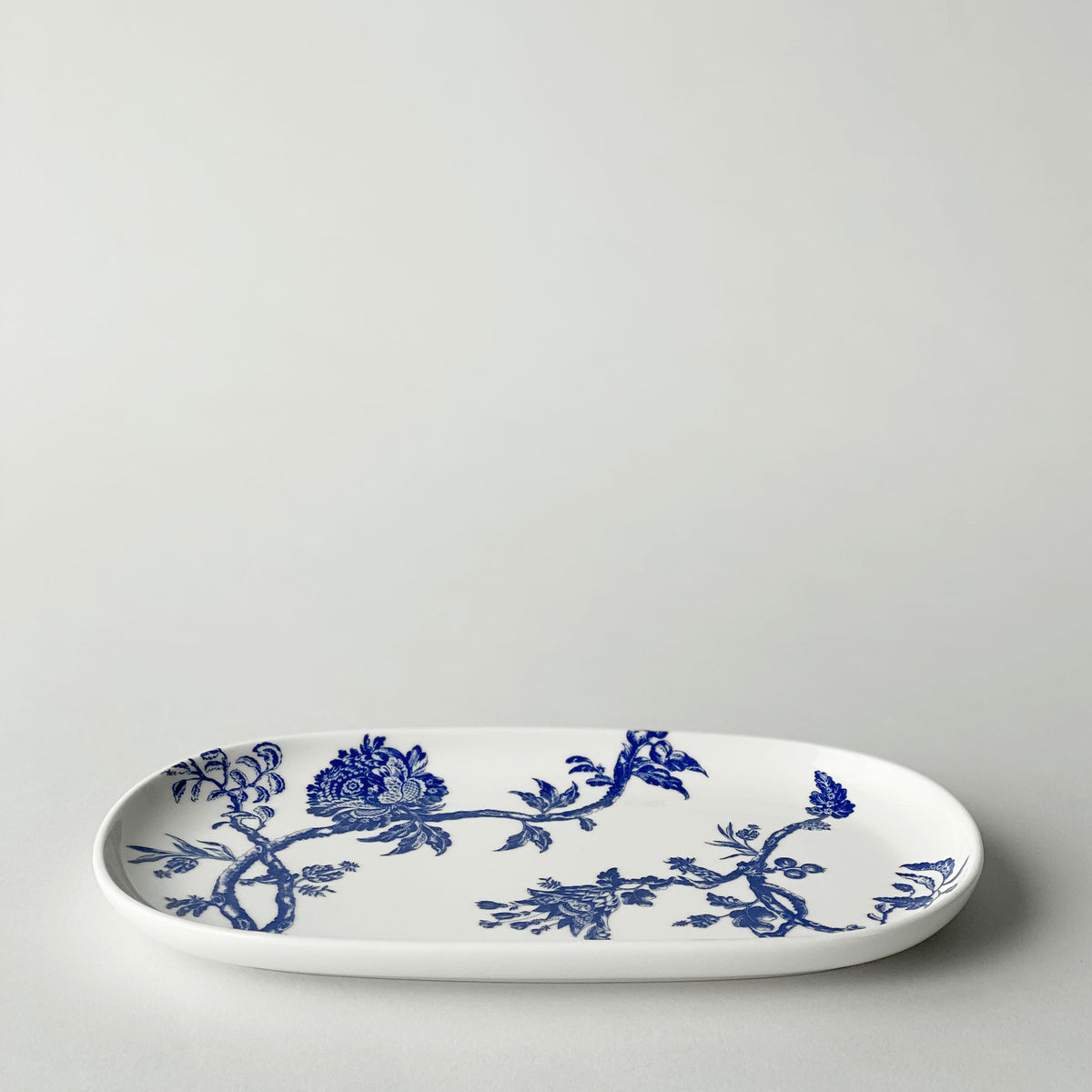 An elegant Caskata Artisanal Home Arcadia Small Oval Tray, perfect for serving appetizers, adorned with delicate blue and white porcelain birds.