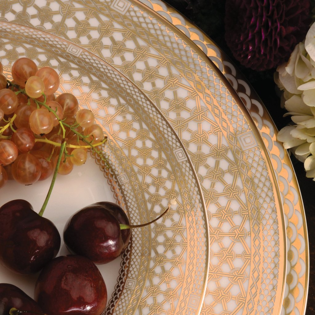 A bone china Hawthorne Gilt Charger Plate with cherries on it by Caskata Artisanal Home.