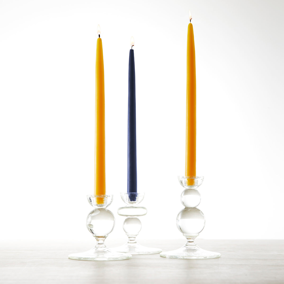 Three glass candle holders with 12&quot; Ochre Taper Candles - Set of 2 by Floral Society on a table.