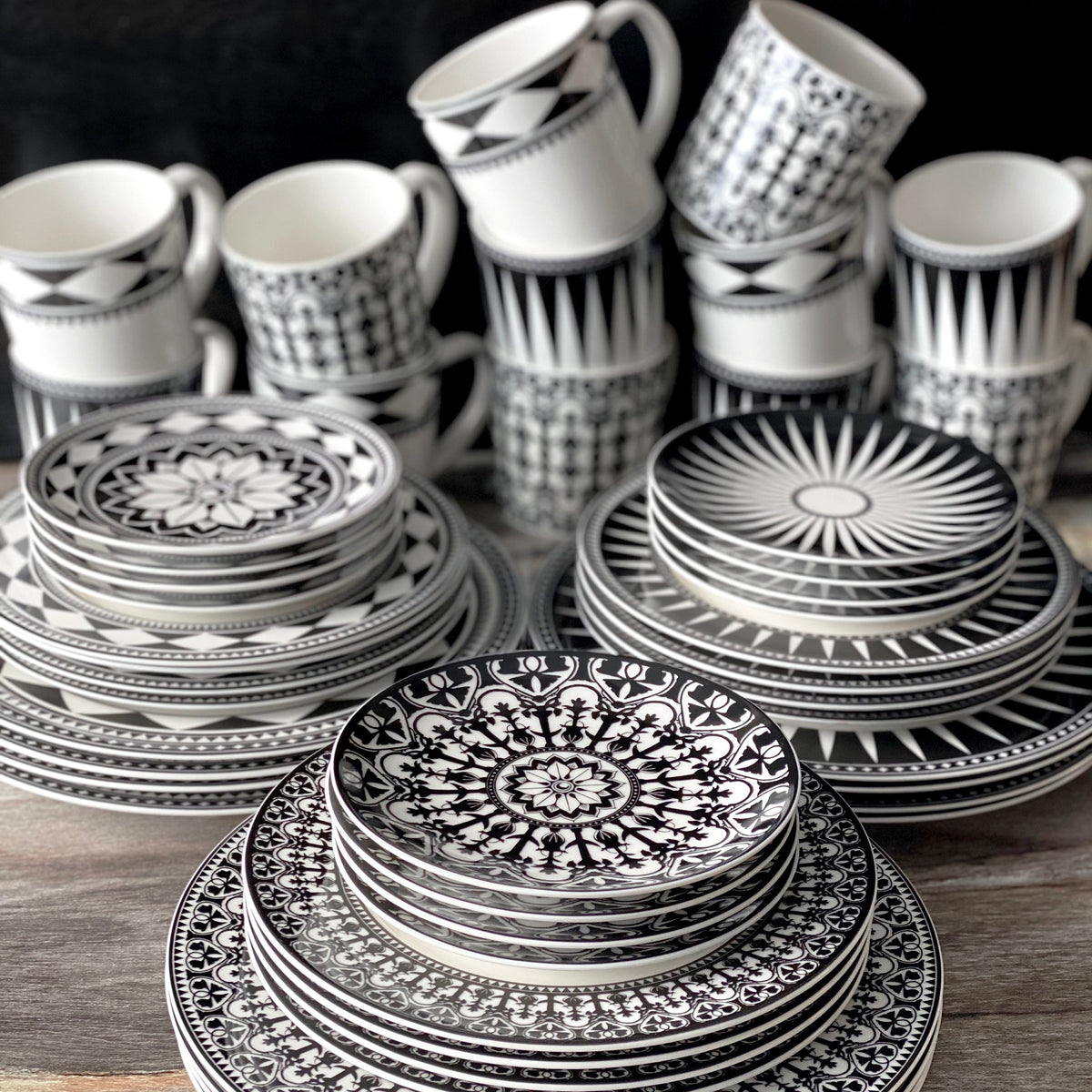 The Casablanca Canapé Plates from Caskata Artisanal Home comprise a stylish set of black and white plates and cups on a table.