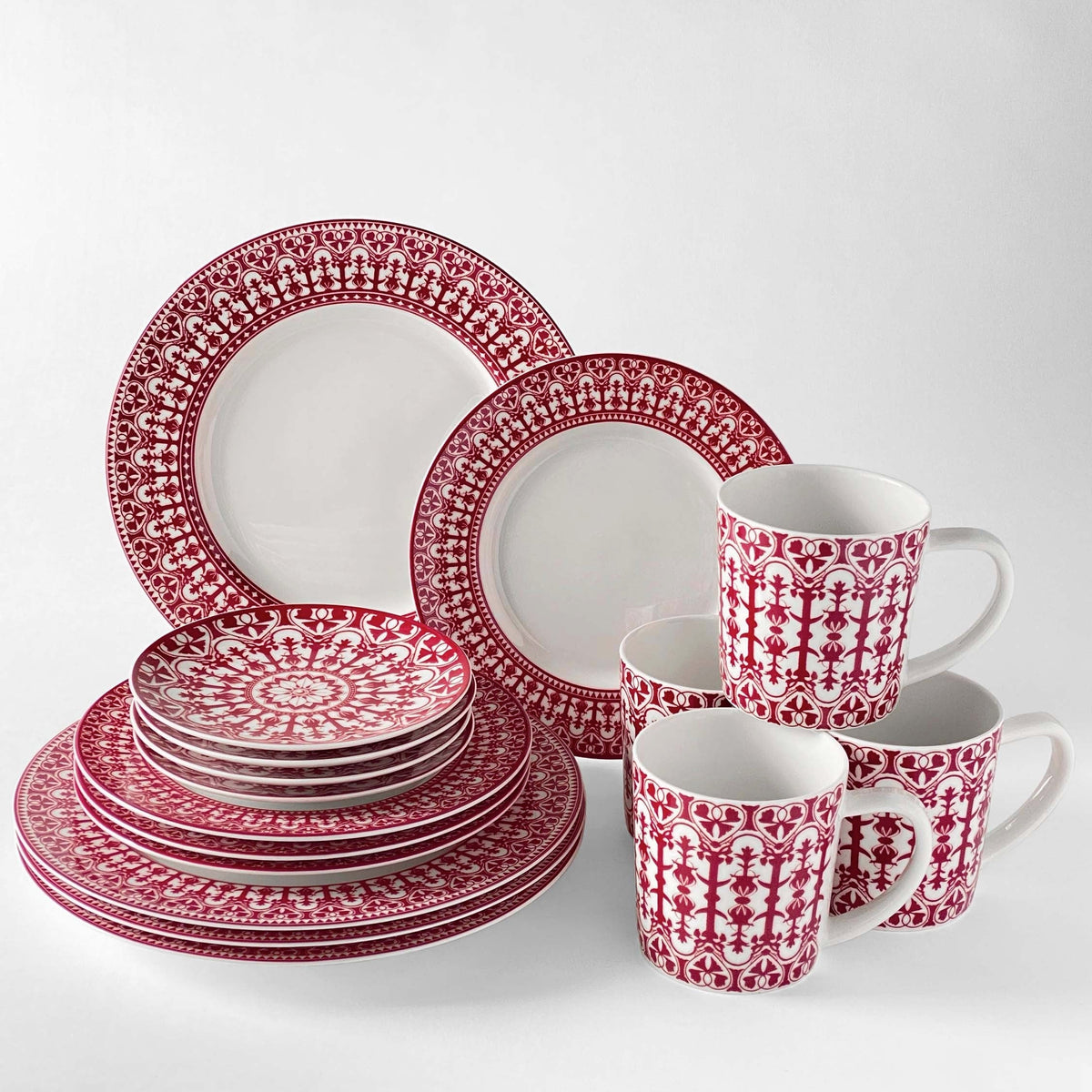 A set of heirloom-quality red and white dinnerware featuring Casablanca Crimson Small Plates by Caskata Artisanal Home, bowls, and mugs with intricate patterns and ornate scrollwork displayed on a white background.