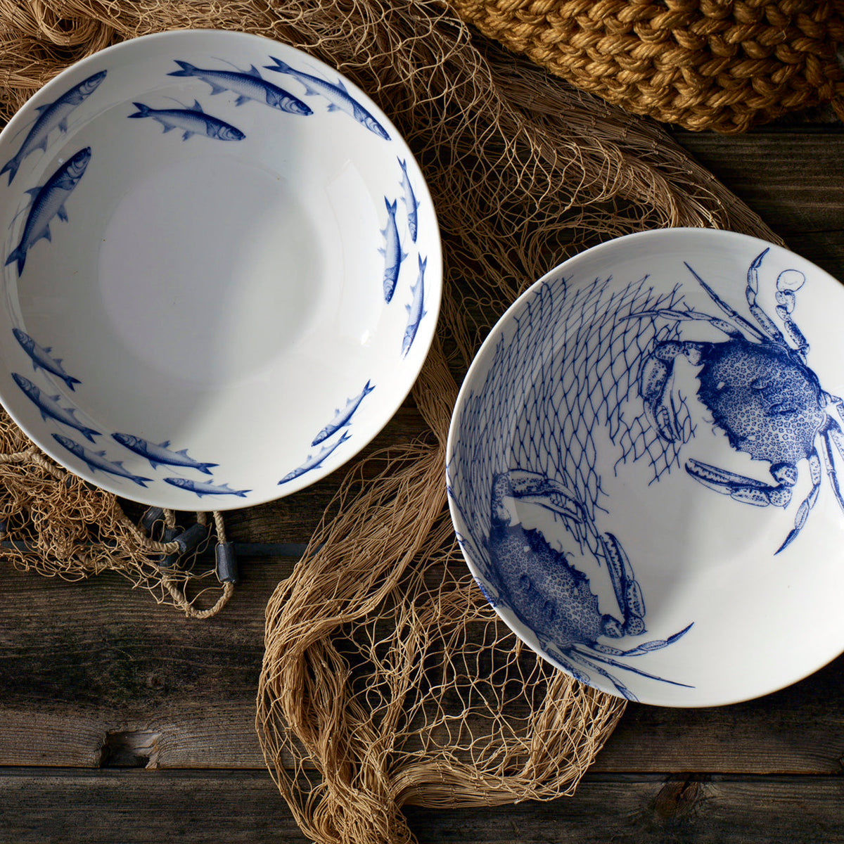 Two School of Fish Wide Serving Bowls by Caskata Artisanal Home on a wooden table.