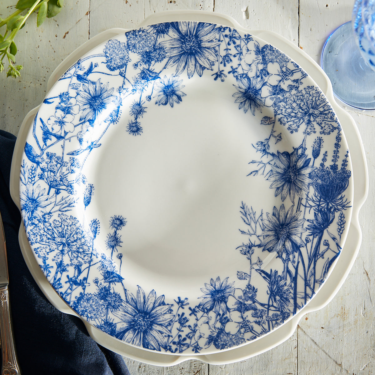 A blue and white Grace White Dinner Plate by Caskata Artisanal Home adorned with graceful flowers.