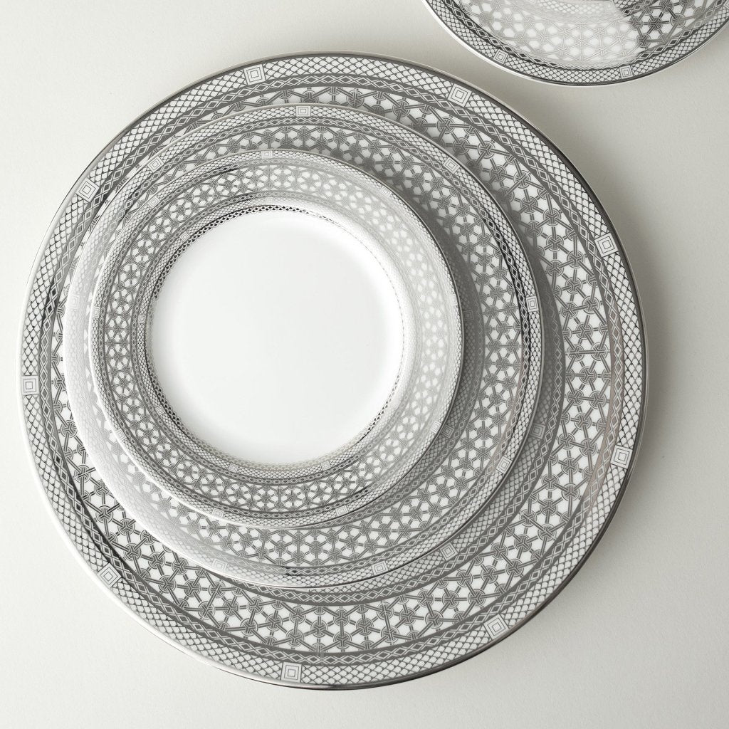 A set of Hawthorne Ice Platinum Dinner Plates and Caskata Artisanal Home silverware on a white surface. The product is elegant and stylish, perfect for formal dinner settings. The shiny silver finish adds a touch of sophistication to any table decor.