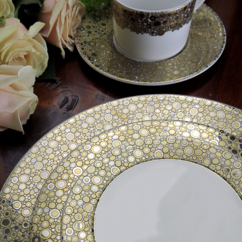 A Caskata Artisanal Home gold plate and cup on a table with Ellington Shimmer roses