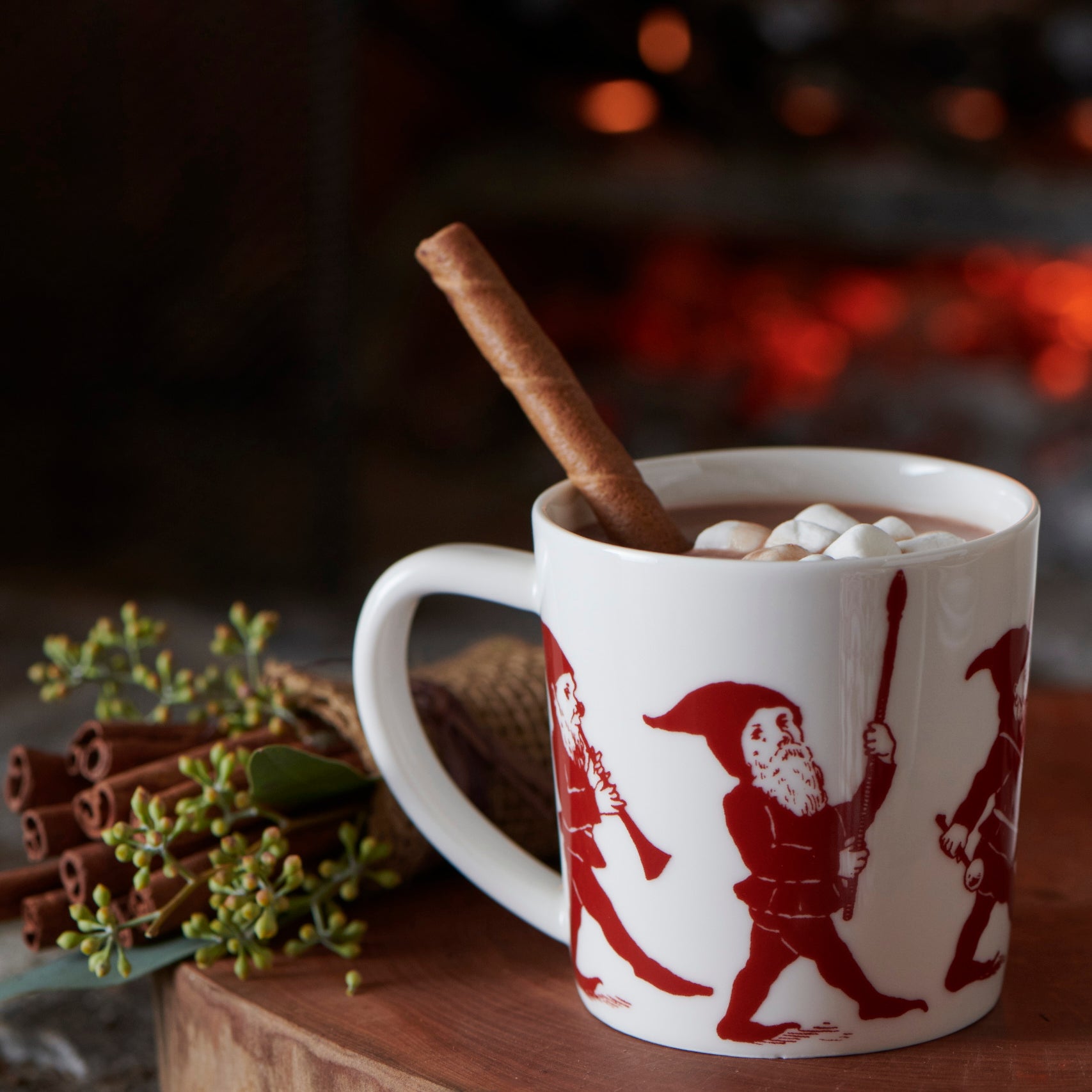 White porcelain Elves Mug with red illustrations of playful elves marching, one playing a drum and another carrying a basket. Perfect for the Caskata Artisanal Home holiday collection.