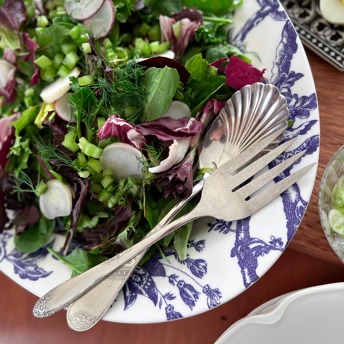 A crisp tossed salad is featured on a blue and white porcelain Arcadia Platter by Caskata.
