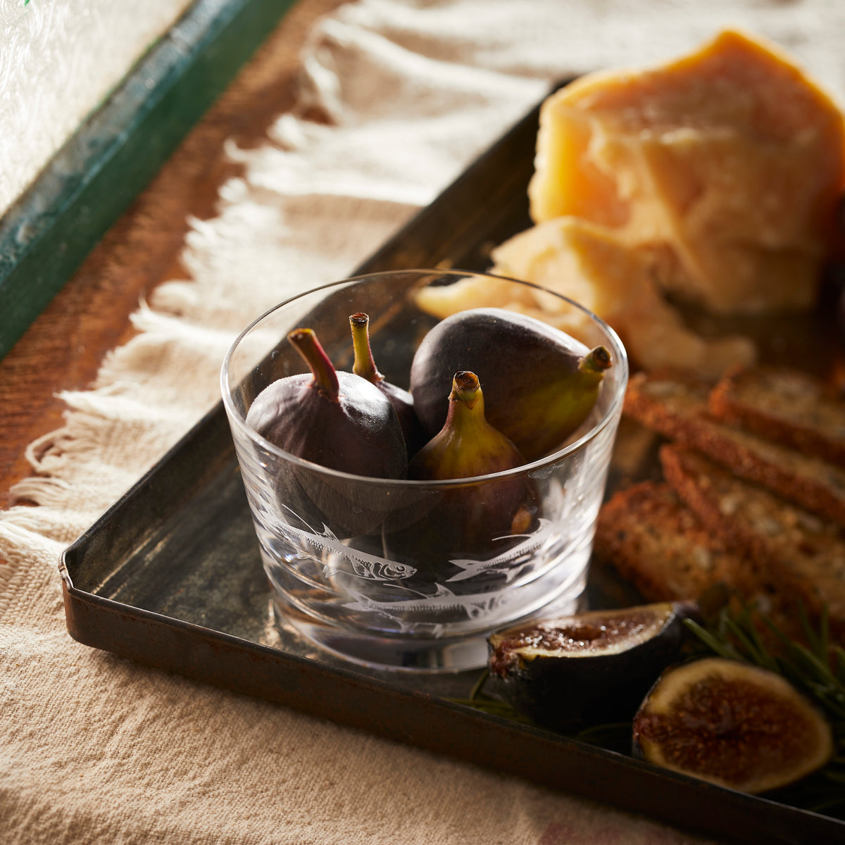 Caskata&#39;s etched crystal School of Fish Tidbit bowl holds fresh figs on an appetizer tray.
