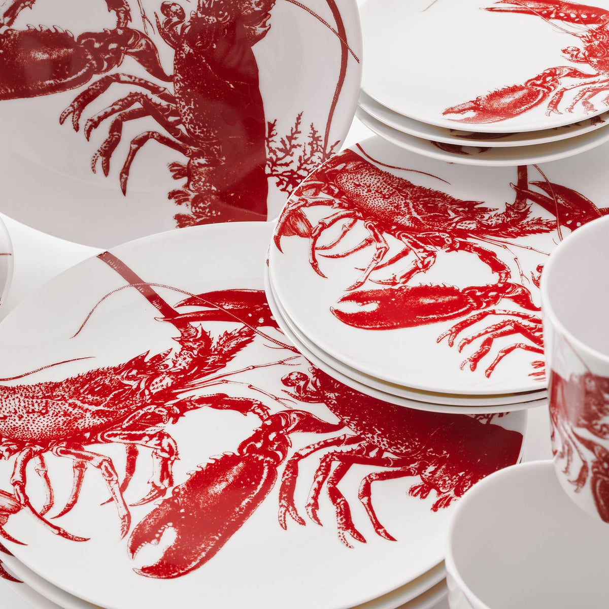 A coastal-style set of Lobsters Table for 4 red and white dinner plates with lobsters on them by Caskata.