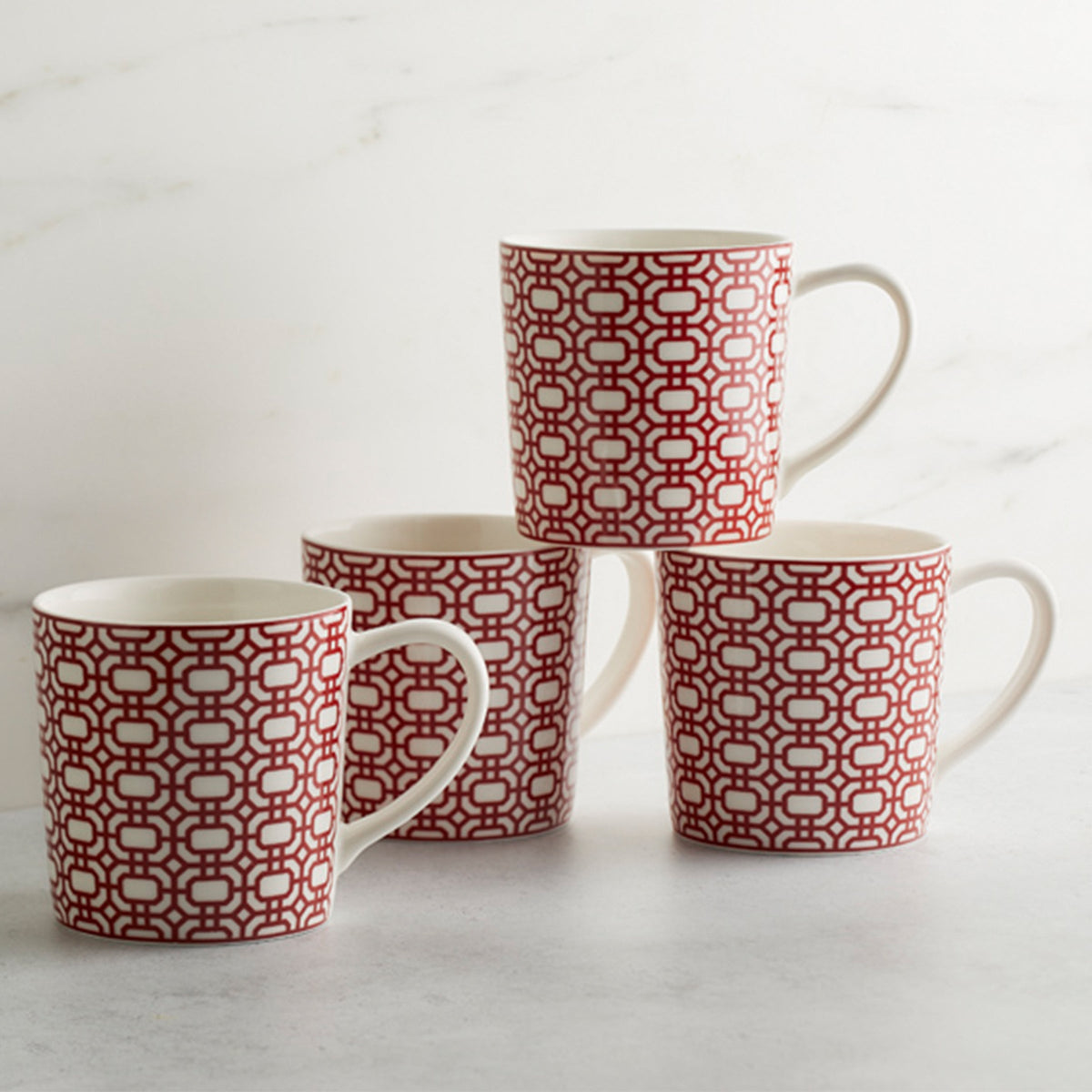 Four Newport Garden Gate Crimson Mugs with red and white designs on them.