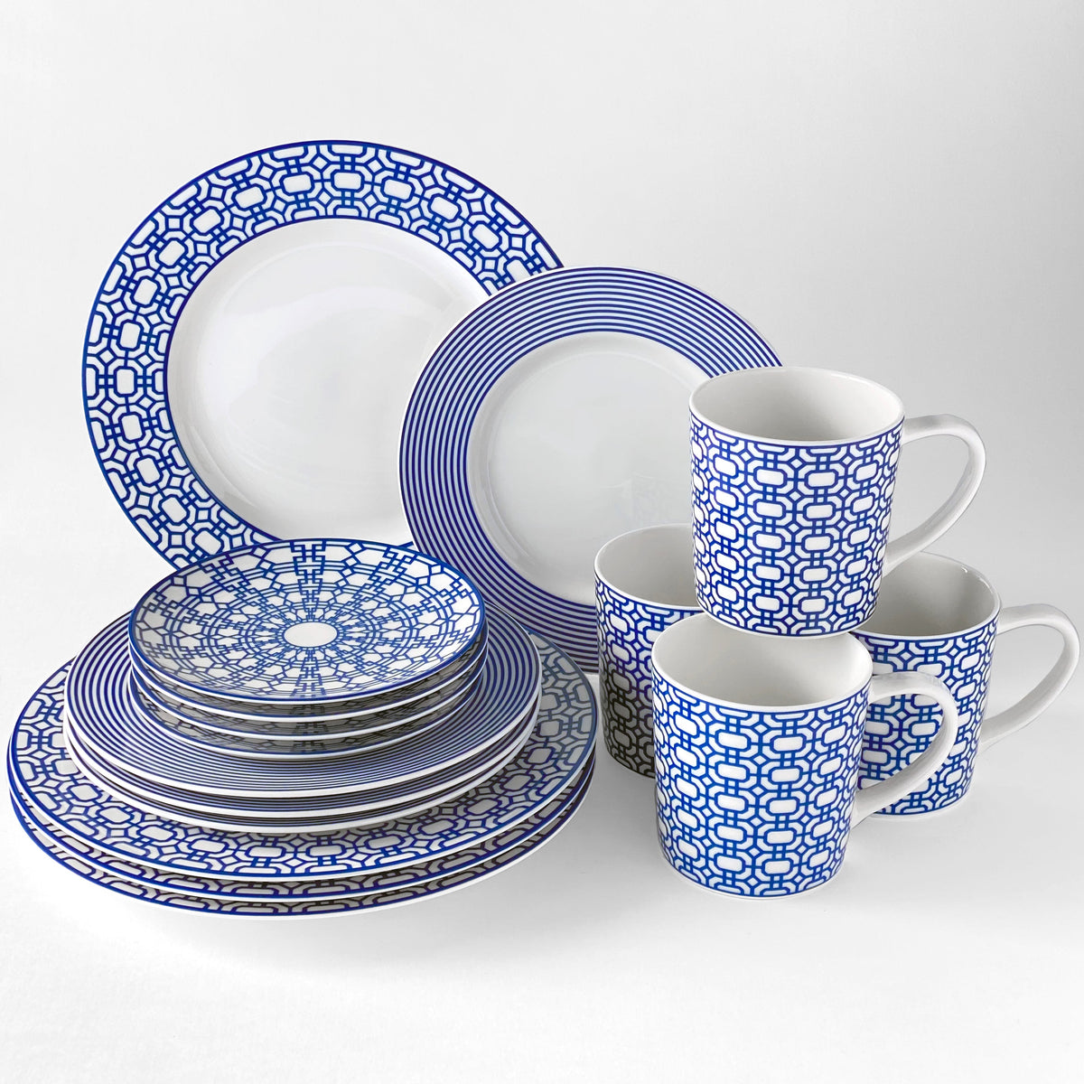 Set of blue and white ceramic dinnerware including Newport Small Plates by Caskata Artisanal Home and mugs, each featuring intricate geometric patterns reminiscent of a Newport Garden Gate. Crafted from premium porcelain, this set seamlessly blends style and durability.