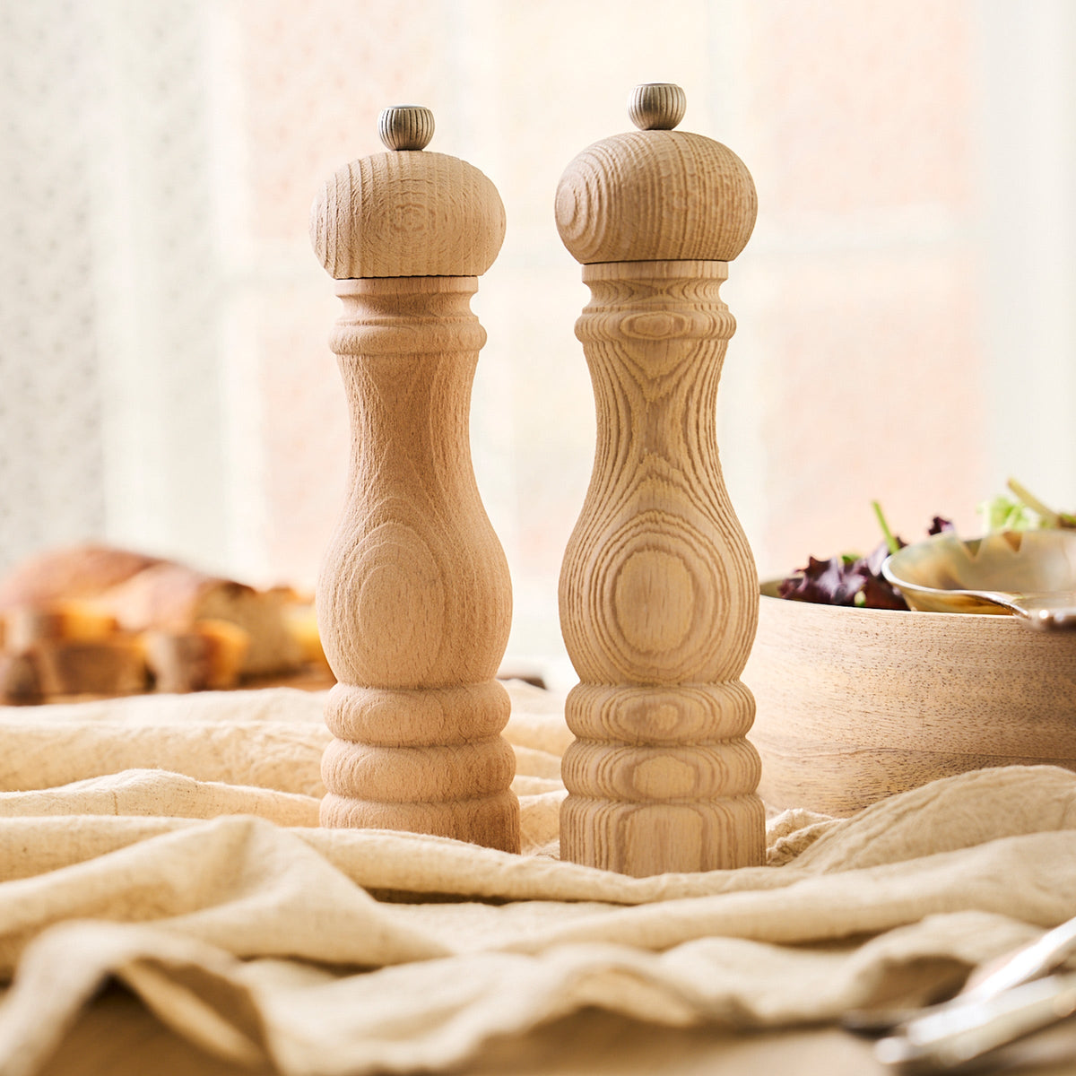 Two Peugeot Paris 9&quot; Natural Salt &amp; Pepper Mills, made from recycled beech wood, on a table.