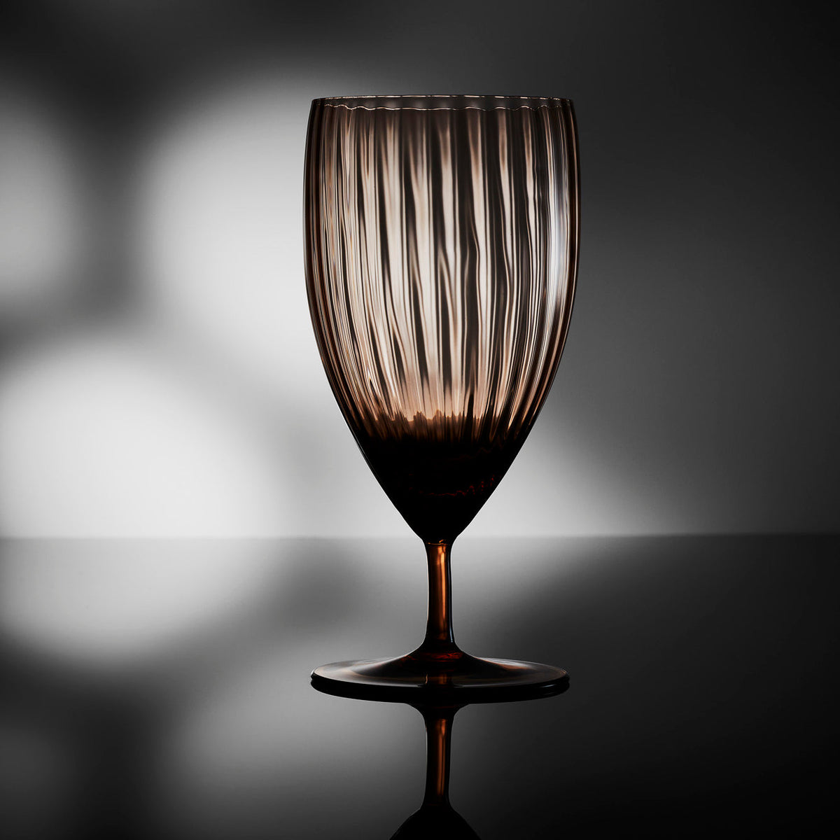Quinn Amber Everyday Glass by Caskata on a moody backlit tabletop.