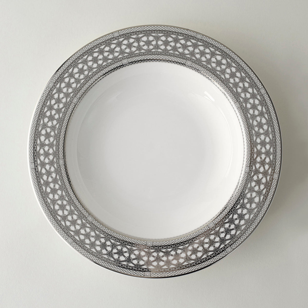 A Caskata Artisanal Home Hawthorne Ice Platinum Rimmed Soup Bowl with an elegant design on it.