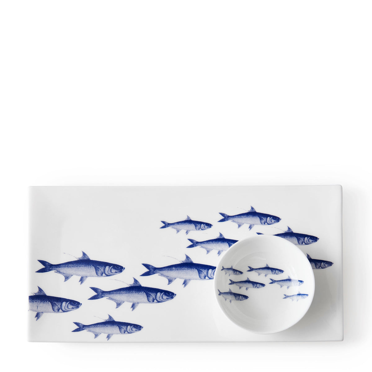 Rectangular white platter with blue fish illustrations, perfect for serving appetizers, accompanied by a small white bowl featuring matching fish images. This charming School of Fish Large Sushi Tray by Caskata adds a touch of elegance to any gathering.