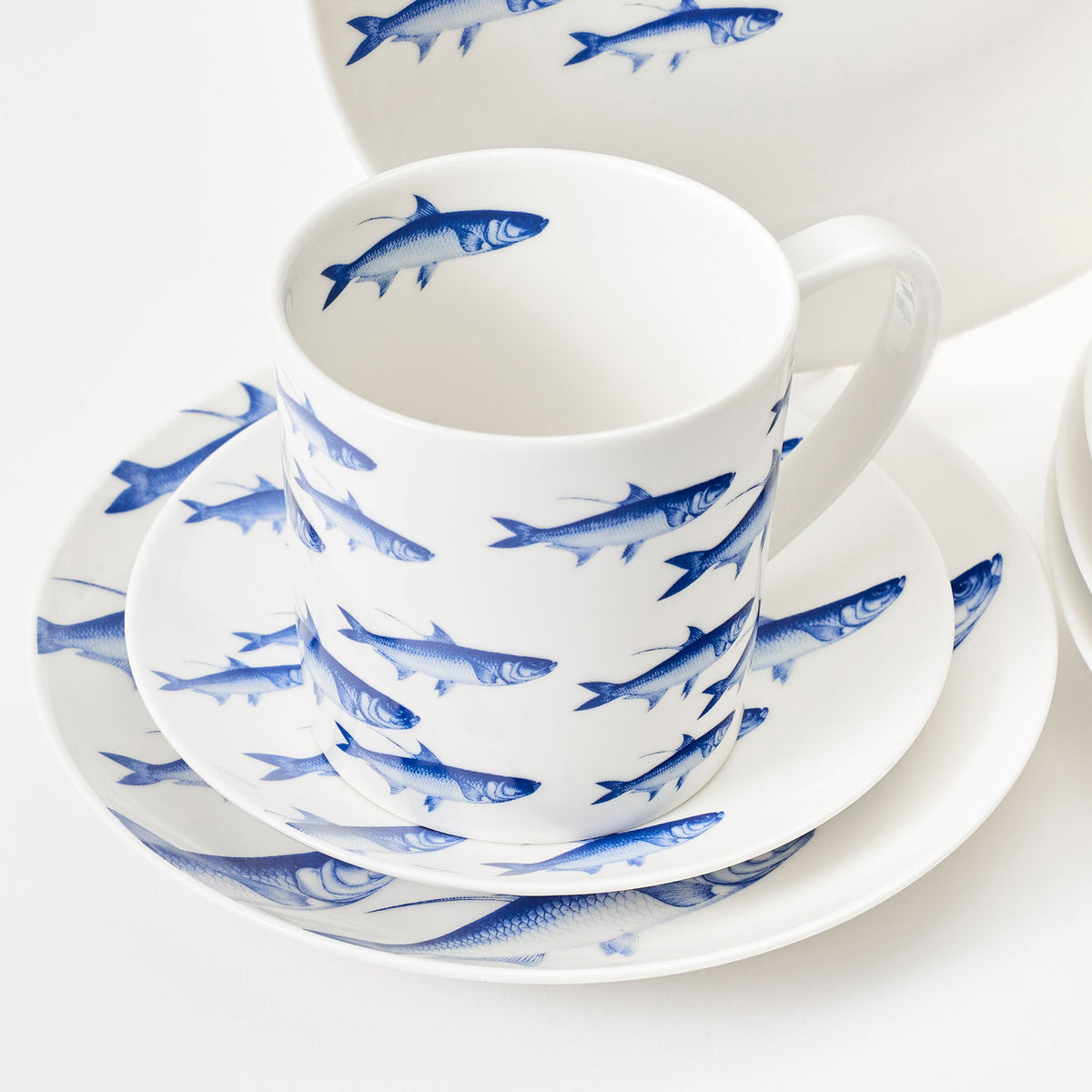 A porcelain set of blue and white plates and cups with fish on them, called the &quot;School of Fish Table for 4&quot; by Caskata.