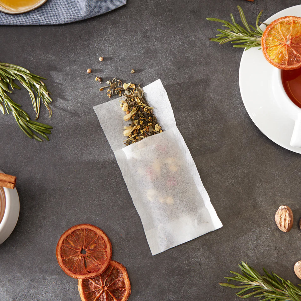 A bag of RSVP International Small Tea Filters with cinnamon sticks and oranges on a table.
