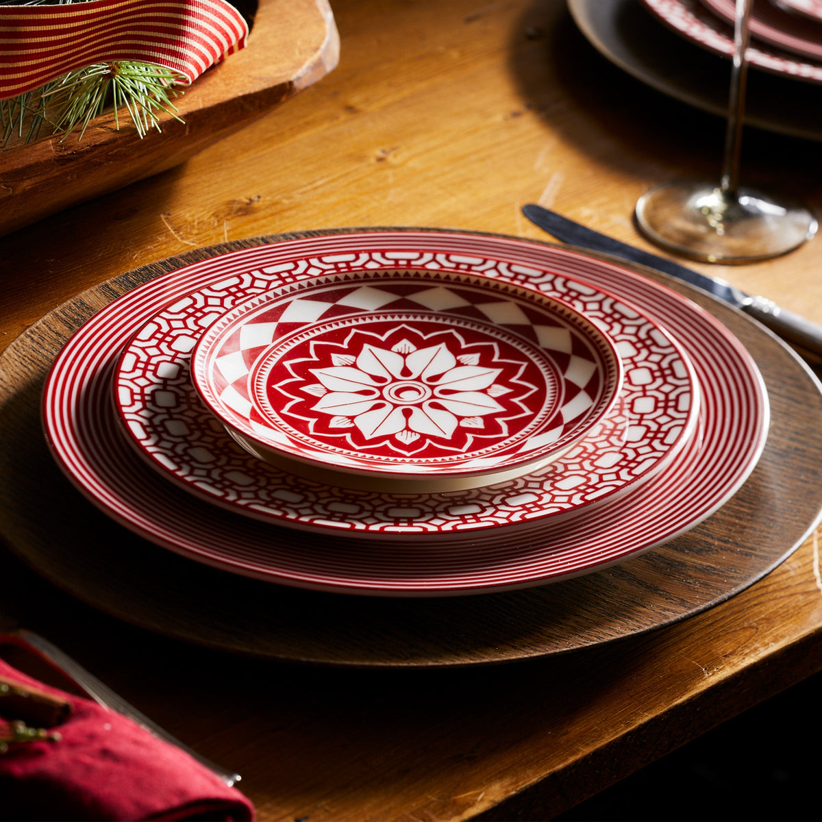 A Caskata Artisanal Home crimson and white plate on a wooden table featuring premium porcelain dinnerware with the Newport Stripe Crimson Dinner Plate pattern.