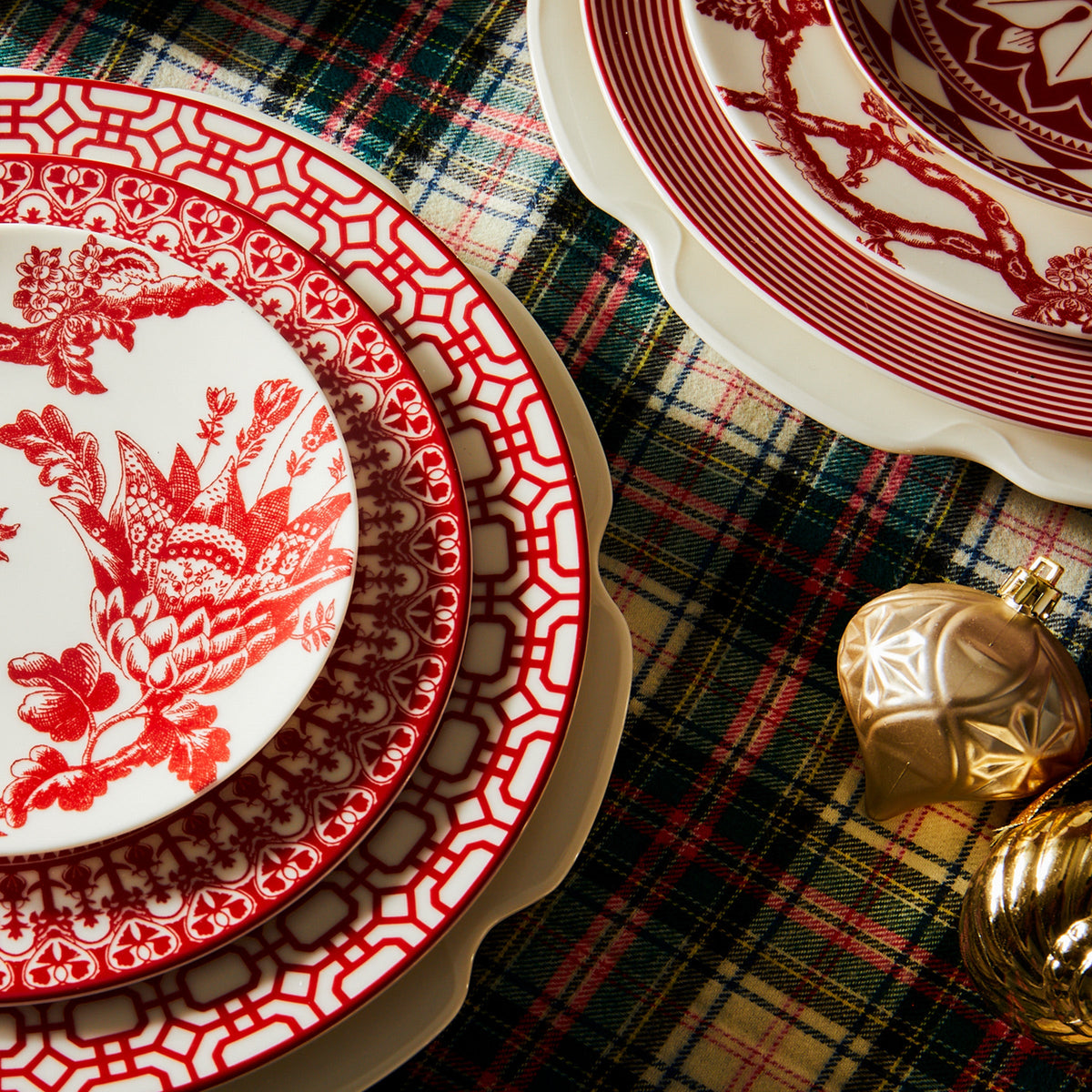 A stack of Newport Garden Gate Crimson Dinner Plates and bowls from Caskata Artisanal Home.