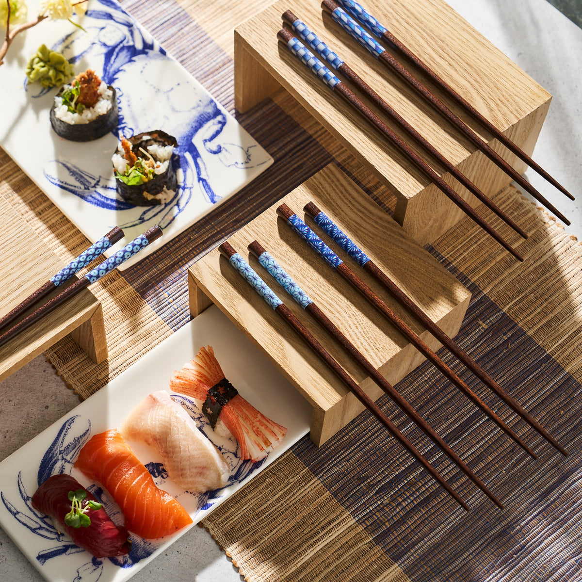 Japanese chopsticks and sushi on a wooden table. The appetizers are beautifully arranged on a Caskata Crab Sushi Tray Large.