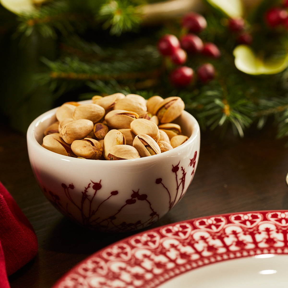 A Winterberries Snack Bowl of pistachios and a plate sit on the table. (Brand Name: Caskata Artisanal Home)