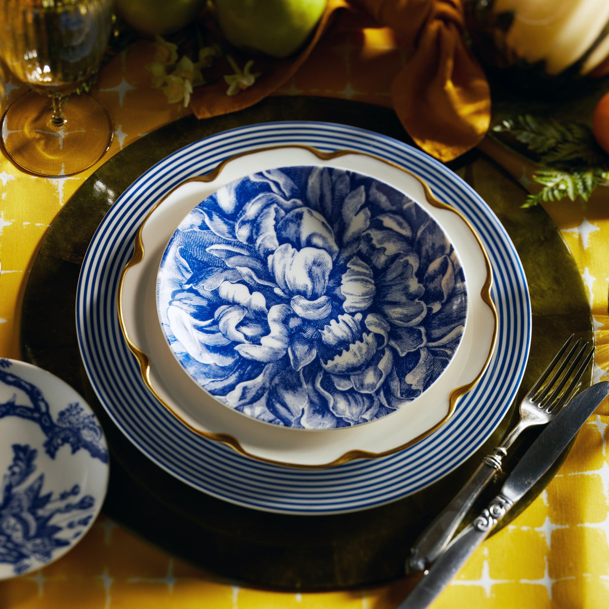 The Peony Blue Full Bloom Canapé Plate (sold as a set of four small plates) is shown as a part of a mixed blue, white and gold place setting.