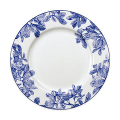 A white ceramic plate with delicate botanical details and blue floral patterns around the rim, this Arbor Rimmed Dinner Plate by Caskata Artisanal Home exemplifies heirloom-quality dinnerware.
