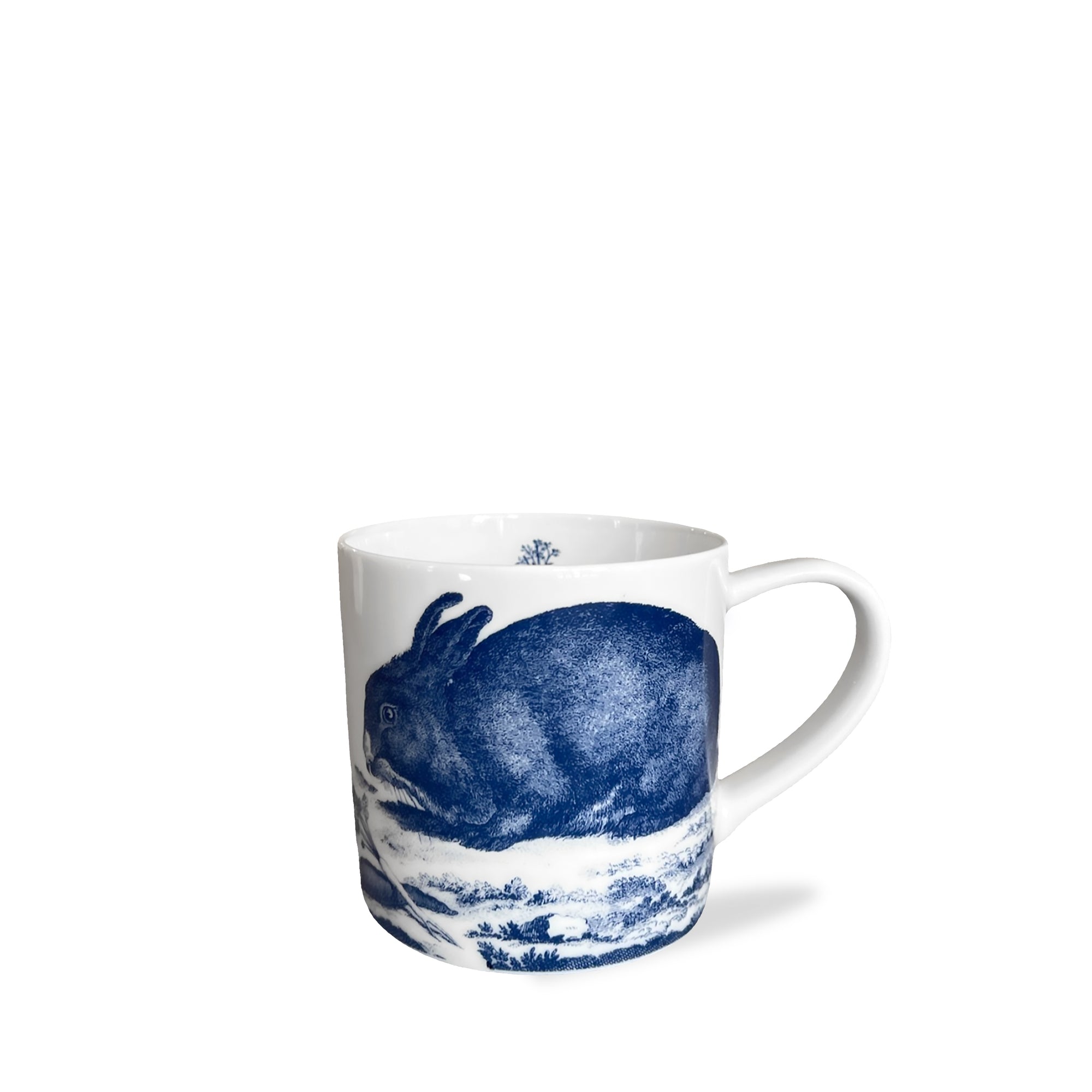 This high-fired porcelain Bunnies Mug from Caskata Artisanal Home features a blue illustration of a rabbit against a nature scene background, making it the perfect Spring-inspired mug for your collection.