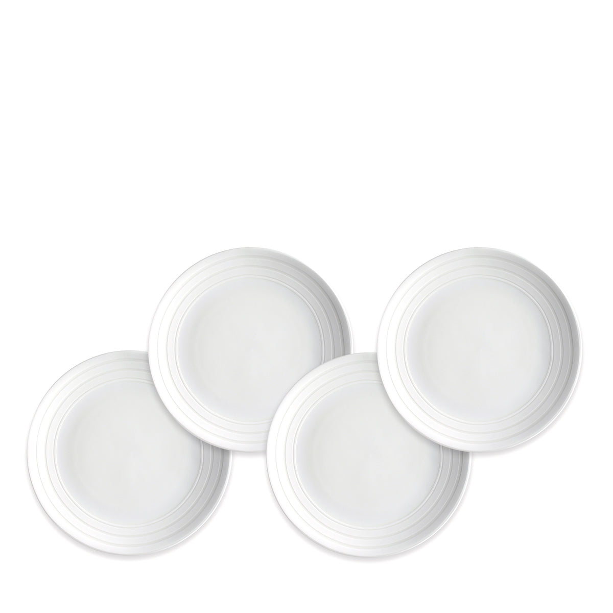 Four white, round plates with simple, concentric circle designs on the edges in the elegant **Cambridge Stripe Small Plates** pattern are arranged in a staggered layout against a plain white background. **Caskata Artisanal Home**