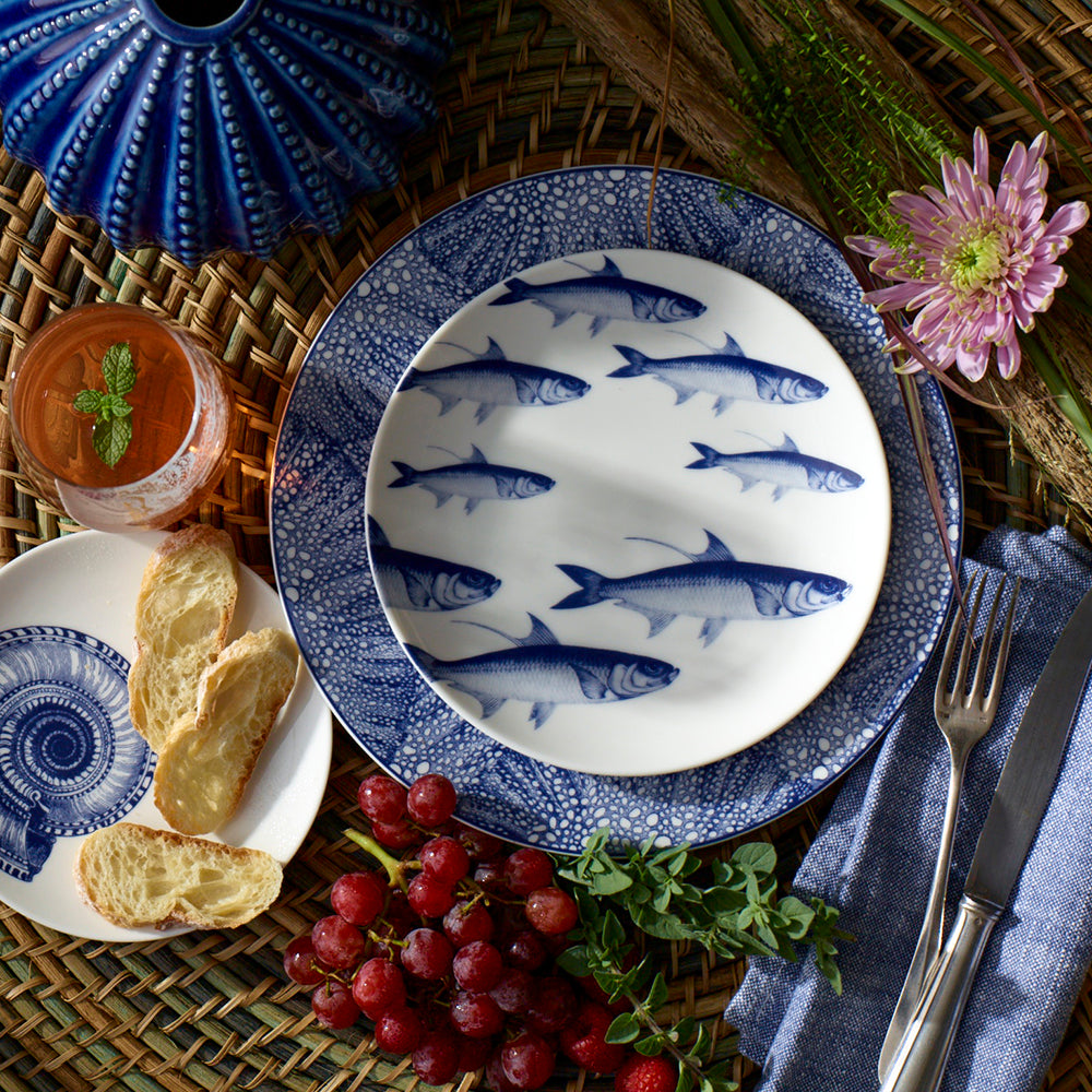 A blue Caskata Artisanal Home accent plate with a School of Fish Coupe Salad Plate on it.