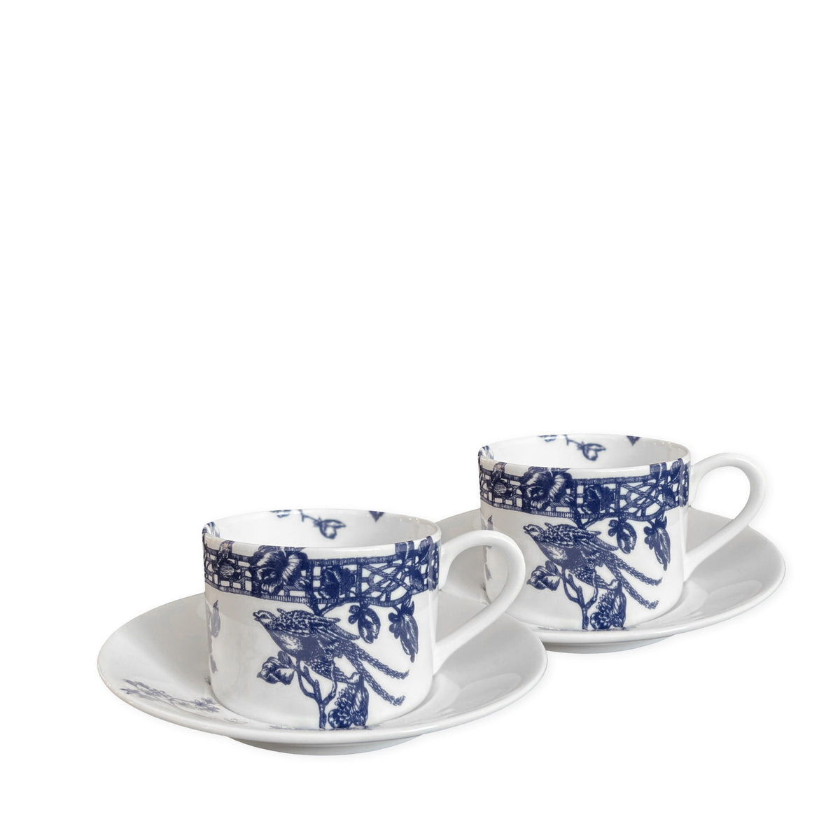 Two white ceramic teacups with blue floral patterns, reminiscent of Chinoiserie Toile, rest on matching saucers. The intricate designs evoke a sense of antique textiles as they sit side by side against a plain background. These are the Chinoiserie Toile Cups &amp; Saucers, Set of 2 by Caskata Artisanal Home.