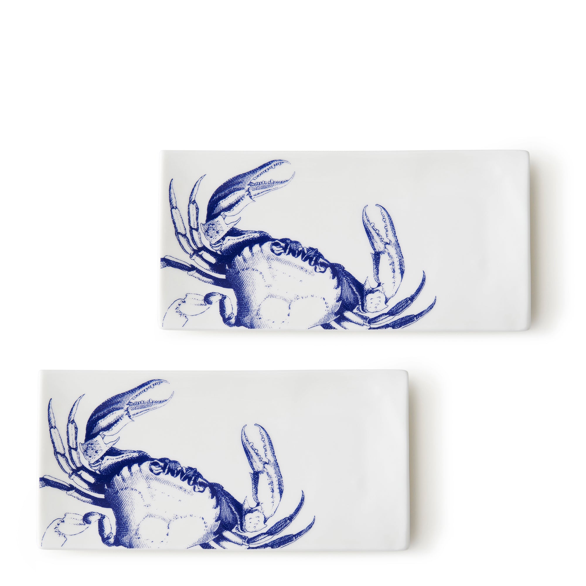 Two rectangular bone china trays featuring a high-style blue crab pattern on one corner. The **Crab Medium Sushi Trays, Set of 2** by **Caskata** are positioned at a slight angle to each other.