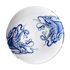 A Lucy Coupe Dinner Plate by Caskata Artisanal Home adorned with blue octopus tentacle designs, reminiscent of Lucy the octopus.
