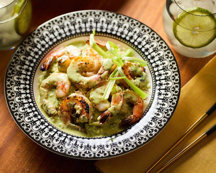 A black and white Casablanca Soup Bowl holds a serving of grilled shrimp with a curry sauce served over rice.