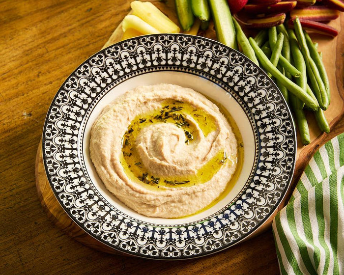 A black and white Casablanca Soup Bowl with a serving of white bean hummus topped with rosemary oil.