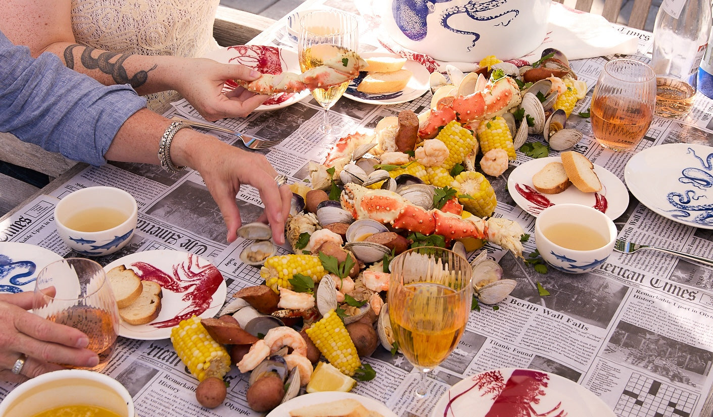 Friends around the crab boil table enjoying dinner on newspaper