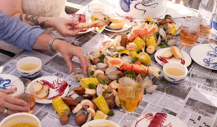 Friends around the crab boil table enjoying dinner on newspaper