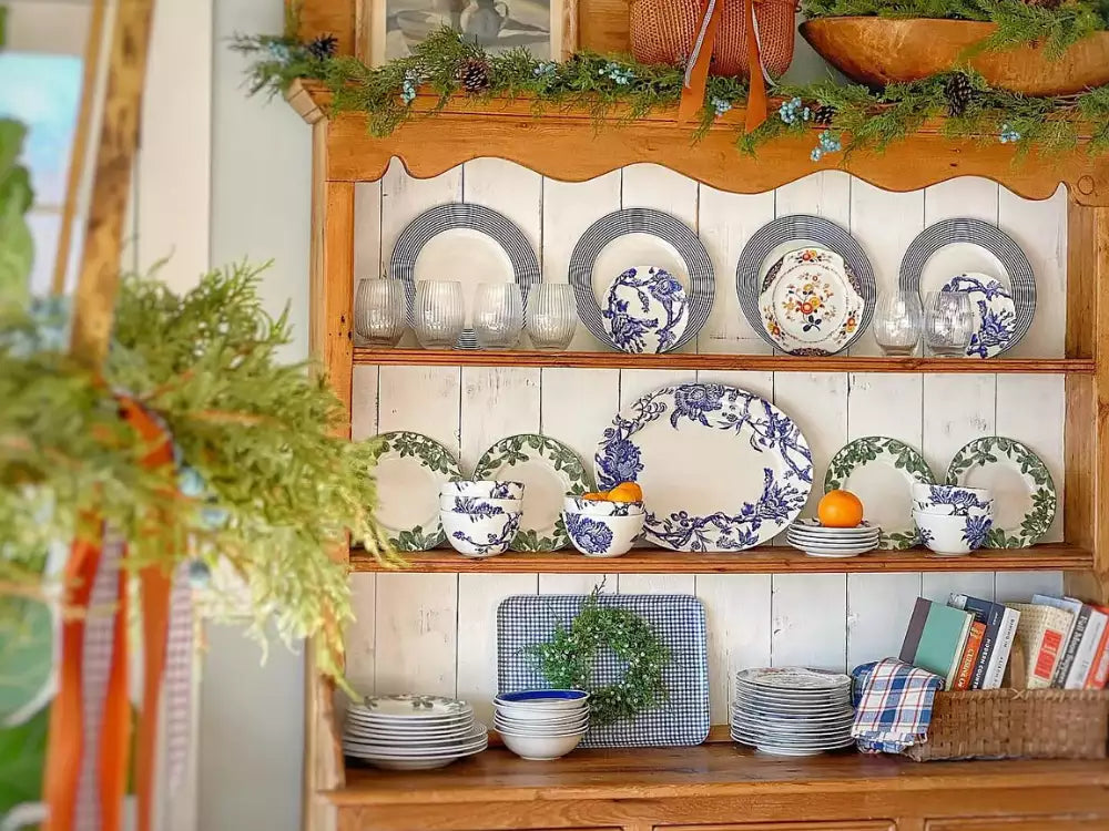 Wooden hutch styled with Caskata dinnerware collections, including blue and white plates, Arbor Green salad plates, and glassware