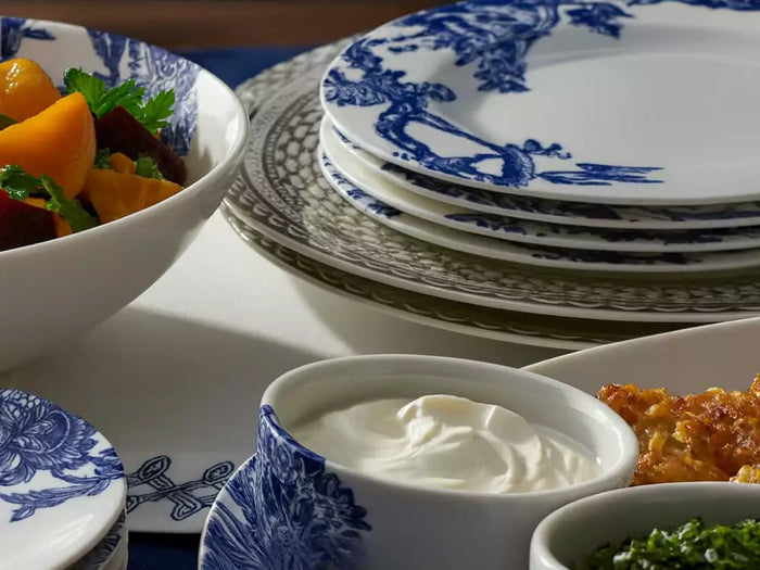 Close-up of a dining table with blue and white porcelain dinnerware, serving bowls filled with colorful vegetables