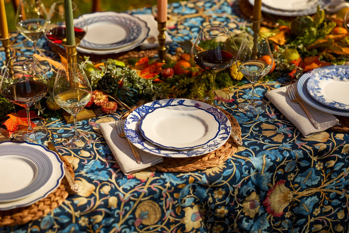 Outdoor dinner table set with Caskata's blue dinnerware and timeless wine glasses