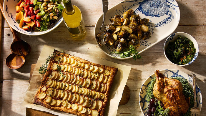 Table filled with homemade dishes including roasted chicken, potatoes, broccoli, and salad.