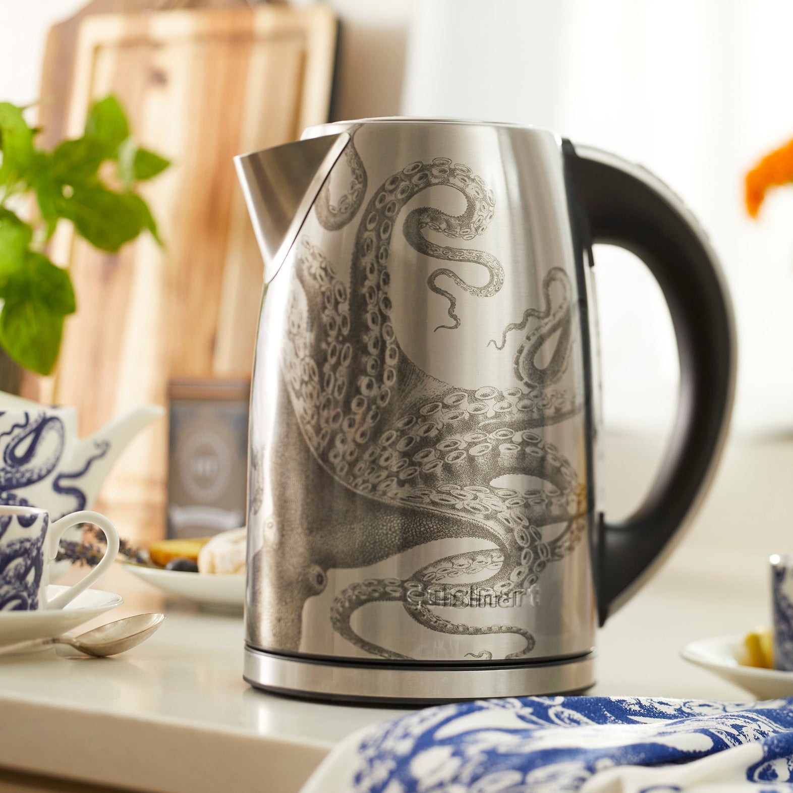Lucy the Octopus Electric Kettle From the Caskata X Cuisinart Limited Edition Collection is shown with dinnerware and etched crystal and textiles in the Lucy pattern from Caskata