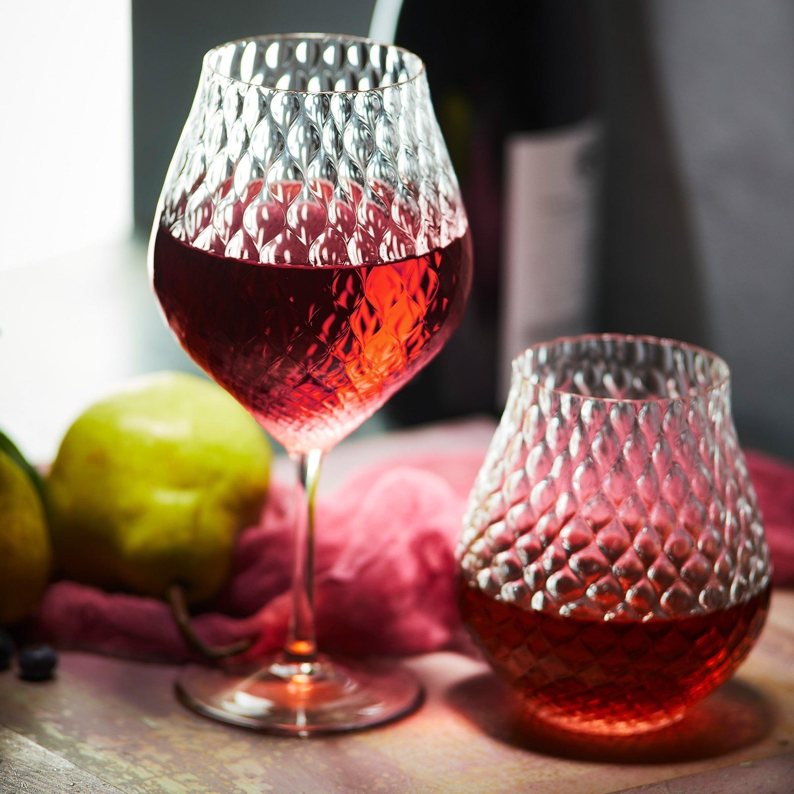 A glass of red wine next to a glass of red liquid.