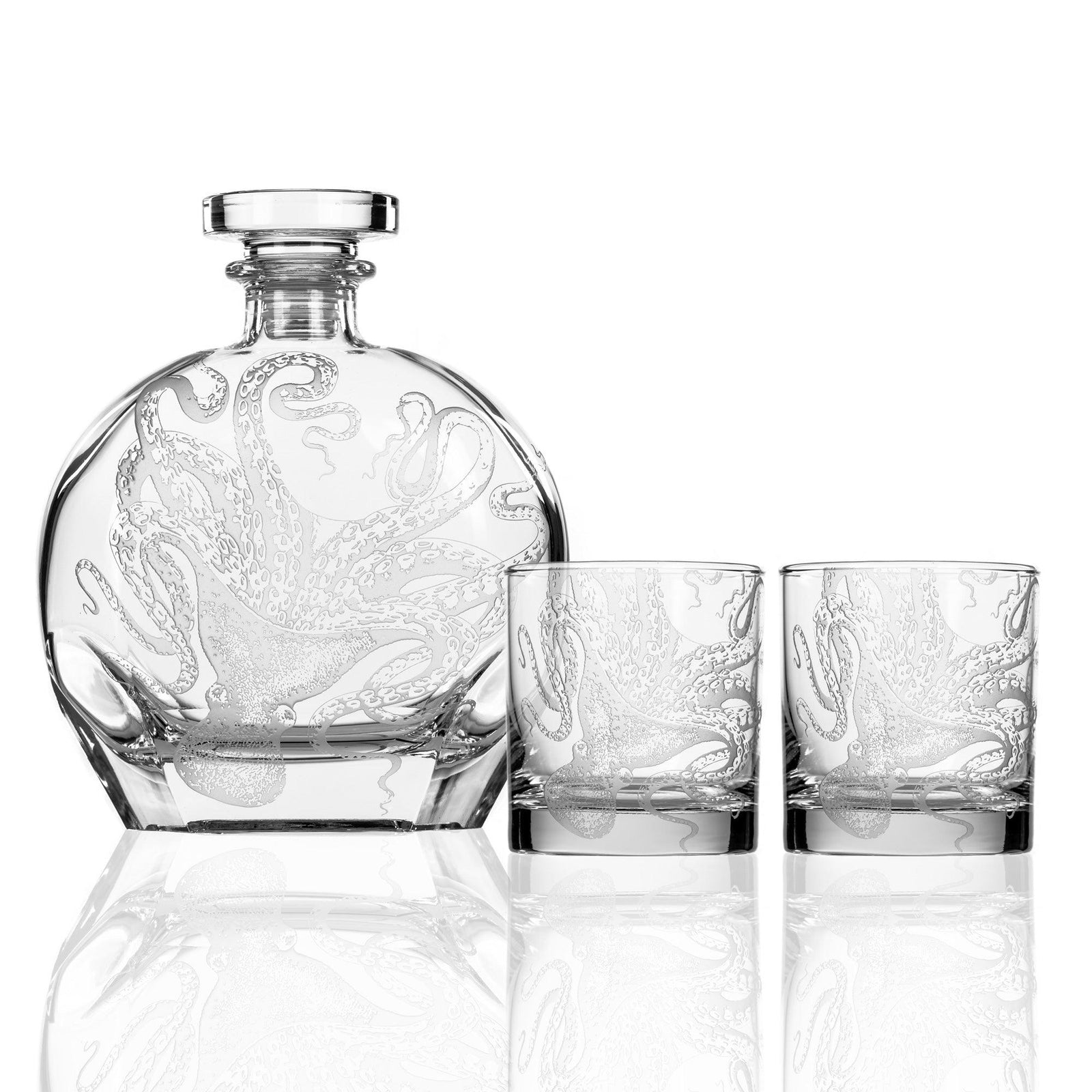 A clear glass decanter with matching design of an octopus and two accompanying glasses, all featuring the same etched octopus motif.