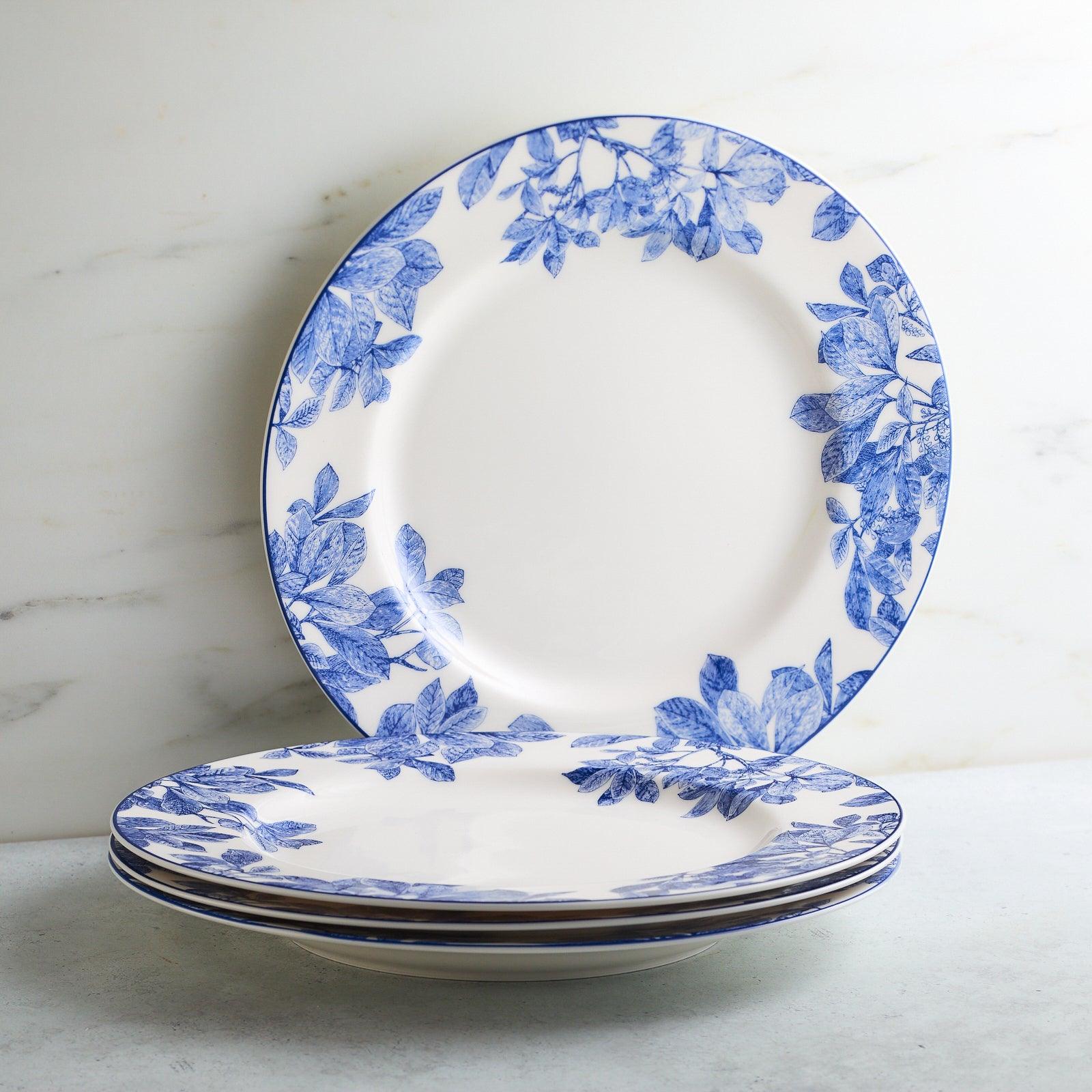 The Caskata Arbor Table for 4 is a 12-piece blue and white porcelain dinnerware set with a leafy branch design. Includes six plates and four bowls. Dishwasher and microwave safe for daily use.